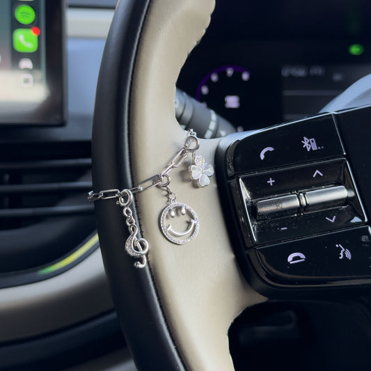 925 sterling silver car steering charm chain with smiley and flower charms attached to a car steering wheel