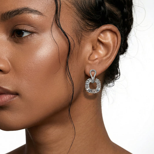 Close-up of a woman wearing silver round earrings with a neutral background