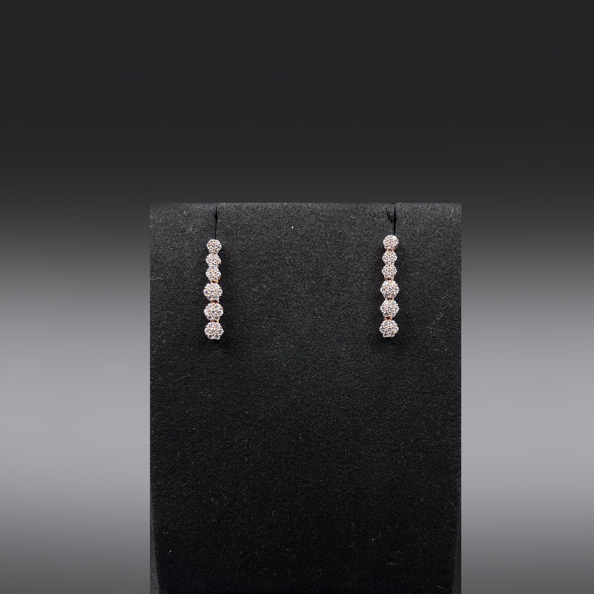 Pair of earrings with zirconia diamonds on a black earring stand