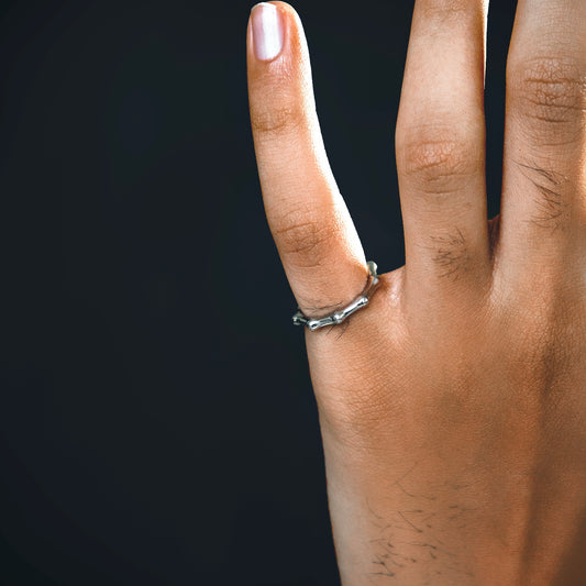 Hand wearing a silver bamboo design ring