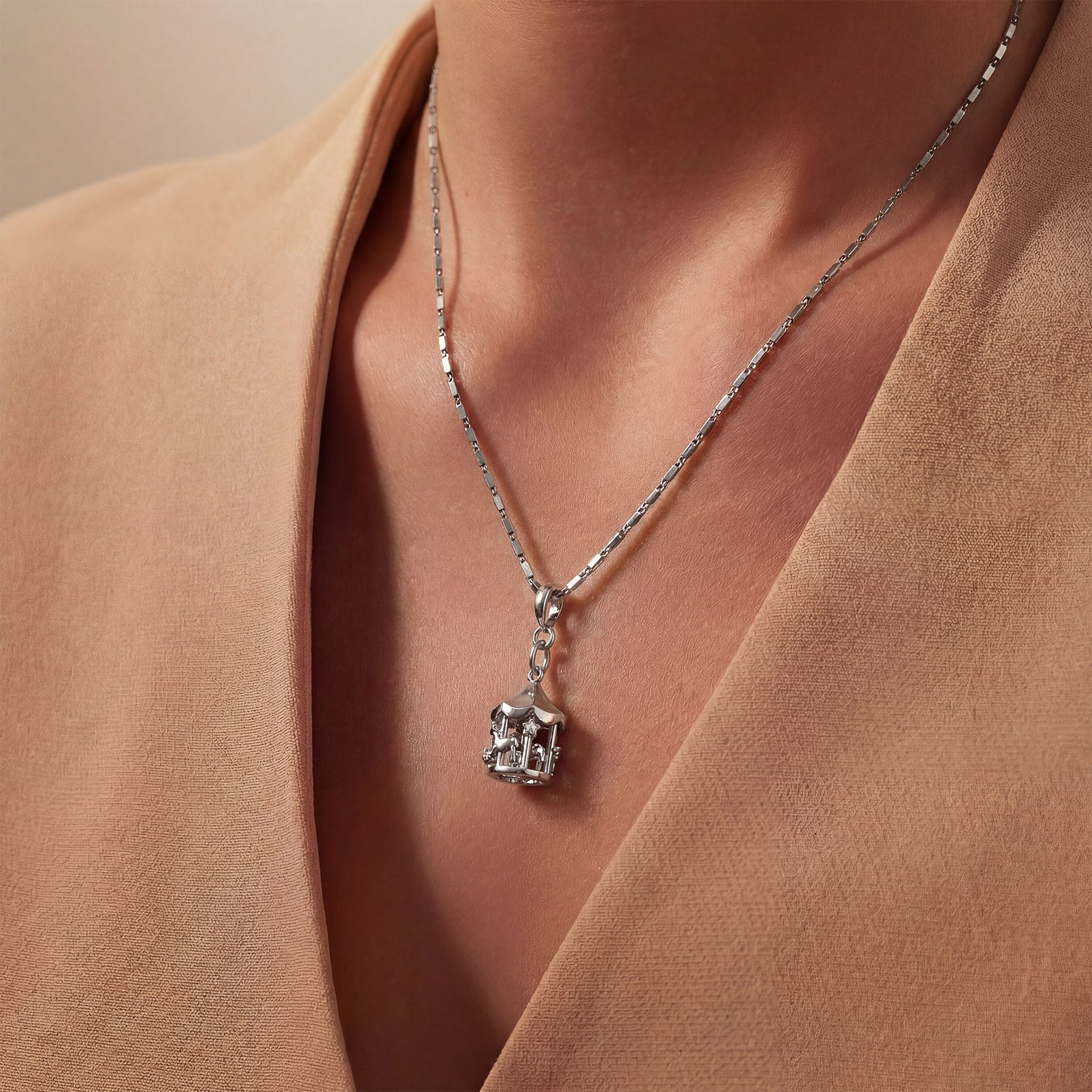 Silver chain with merry go round charm on a person wearing a beige top. Merry go round charm, silver charms, sterling silver charms, charm bracelet, charm chain