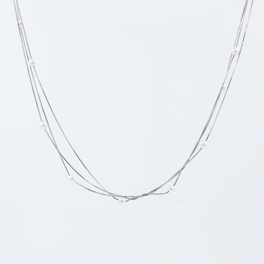 A silver pearl chain with a triple chain design, featuring spaced out pearls on a white background.