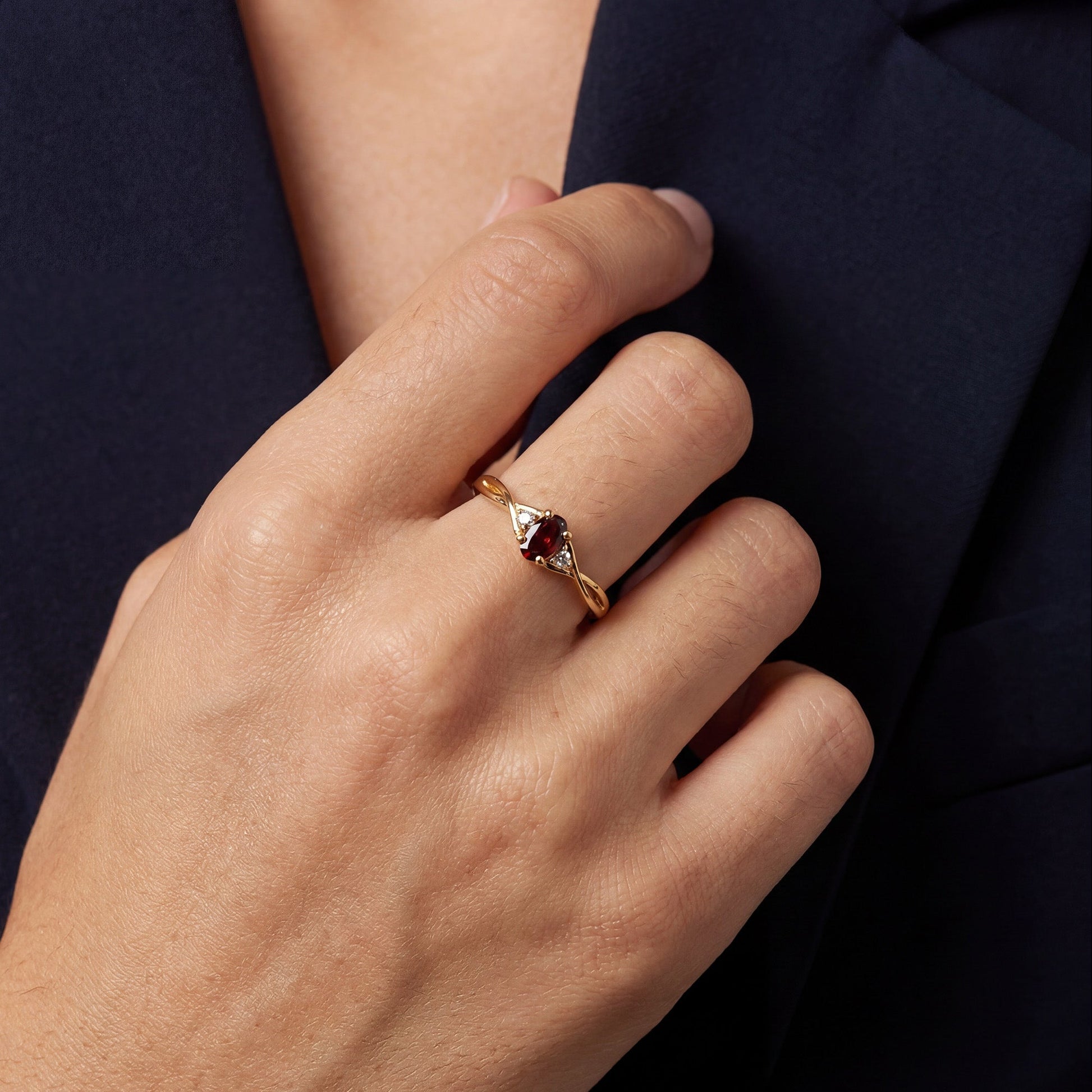 Gold ring with a red gemstone on a person's finger against a dark textured background