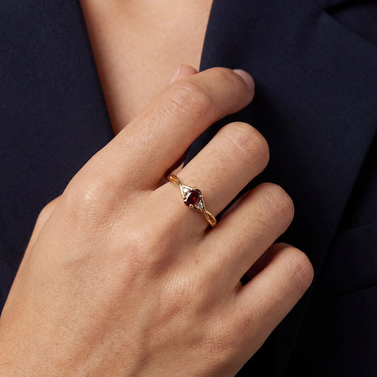 Gold ring with a red gemstone on a person's finger against a dark textured background. this is a perfect ring for wearing daily for the gold jewellery girlies out there