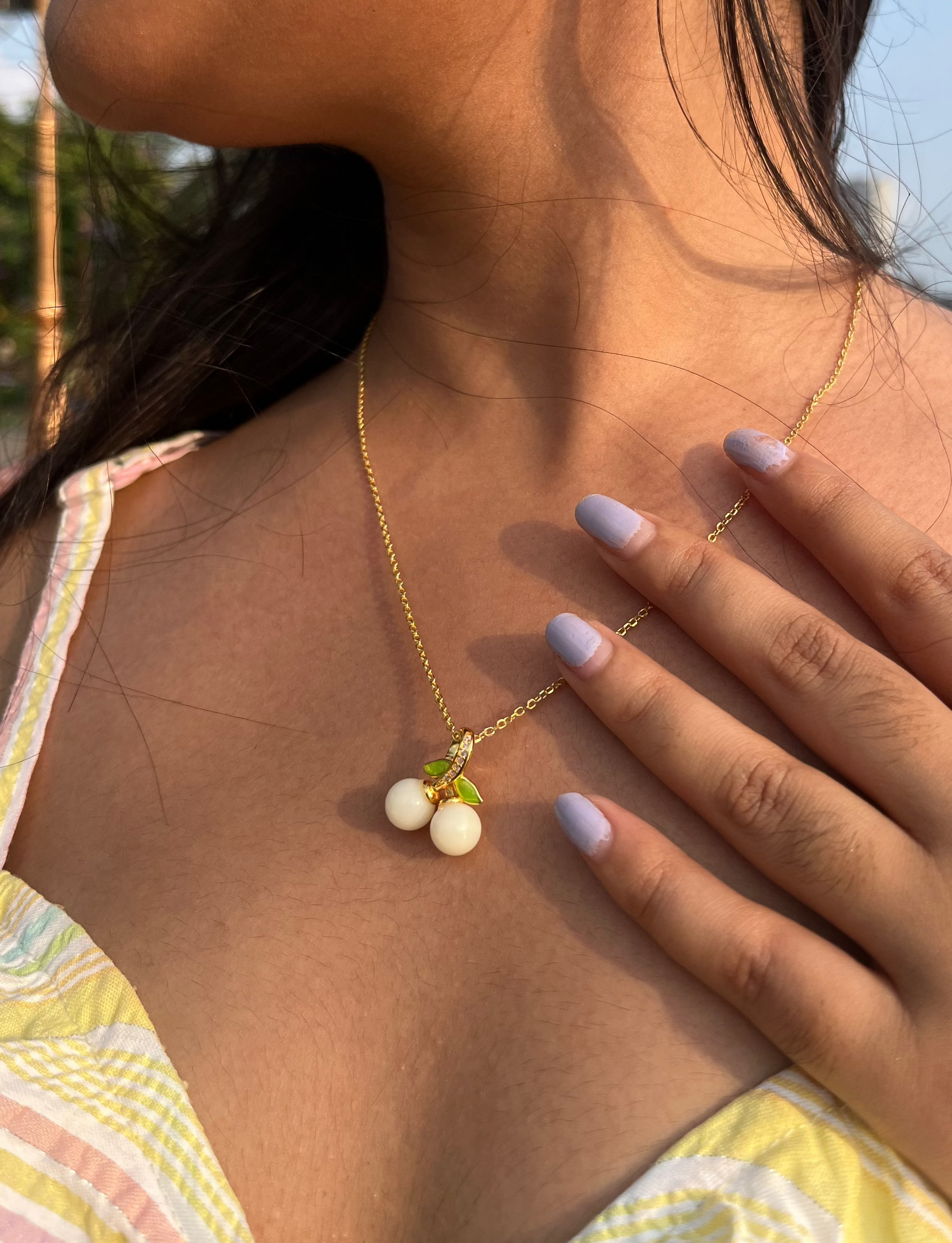 Sterling silver rose gold plated chain and pendant shape of berries on a model with natural lighting and yellow dress