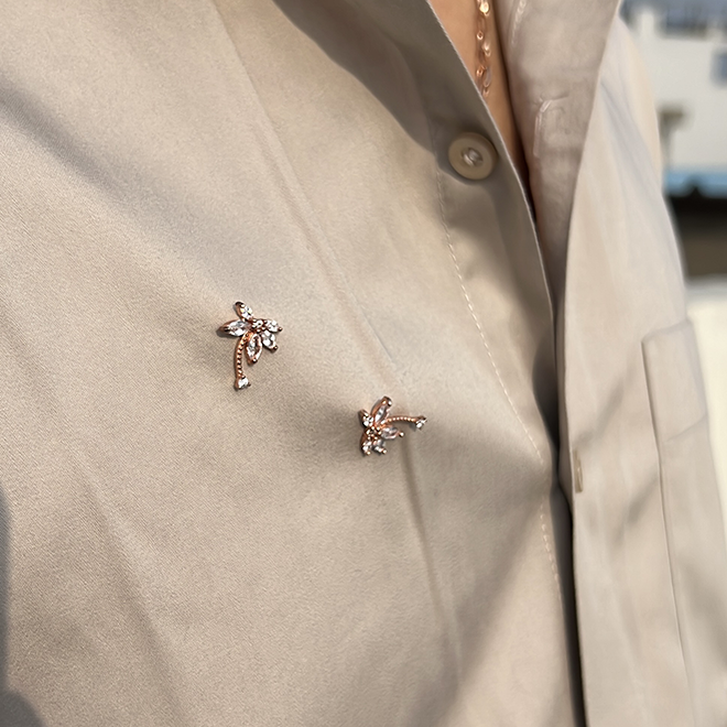 Silver coconut tree studs in rose gold, as a brooch on a beige shirt
