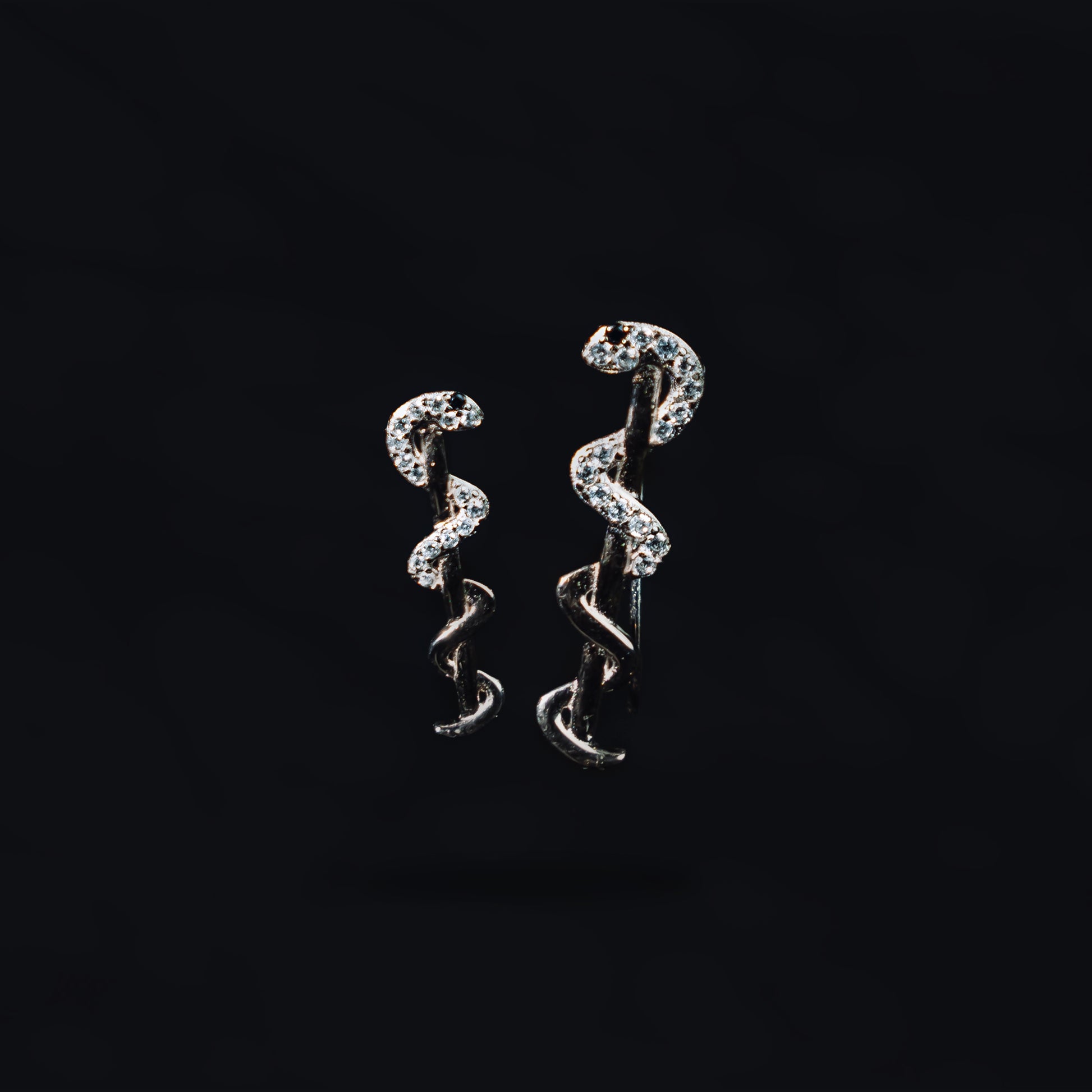 Sterling silver snake ear cuff earrings on black background