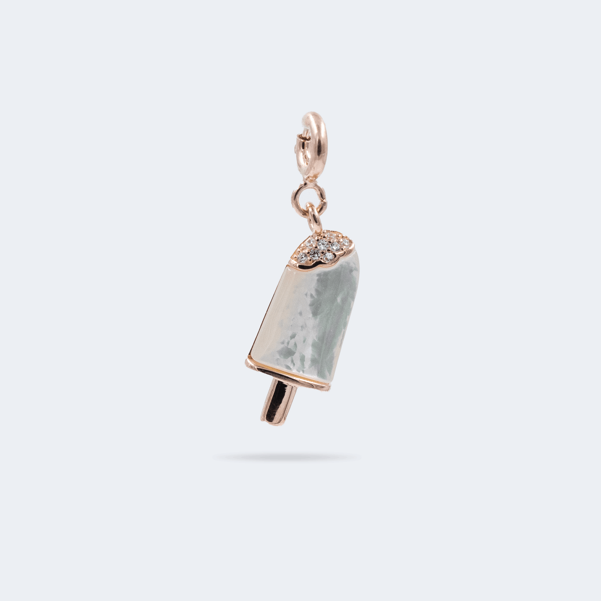 A silver popsicle-shaped charm with a rose gold-colored stick and tip, adorned with small zircon stones on the top and mother of pearl 