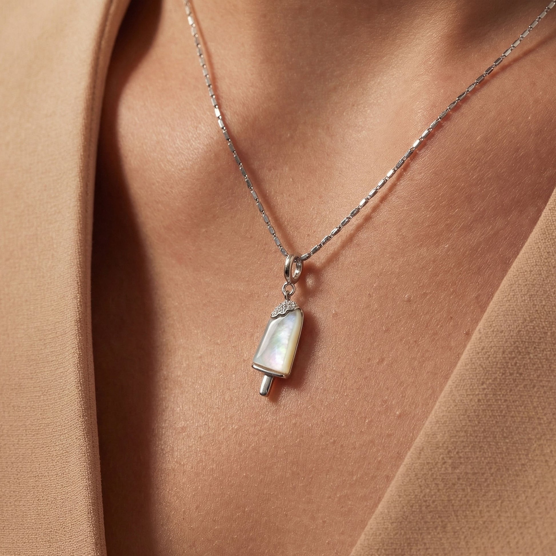 Woman wearing a 925 silver chain with an ice cream - popsicle charm in a warm-toned setting