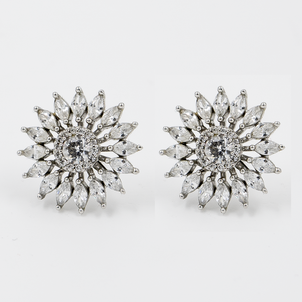A pair of silver stud earrings designed with a central stone surrounded by leaf-shaped stones creating a sunburst effect.