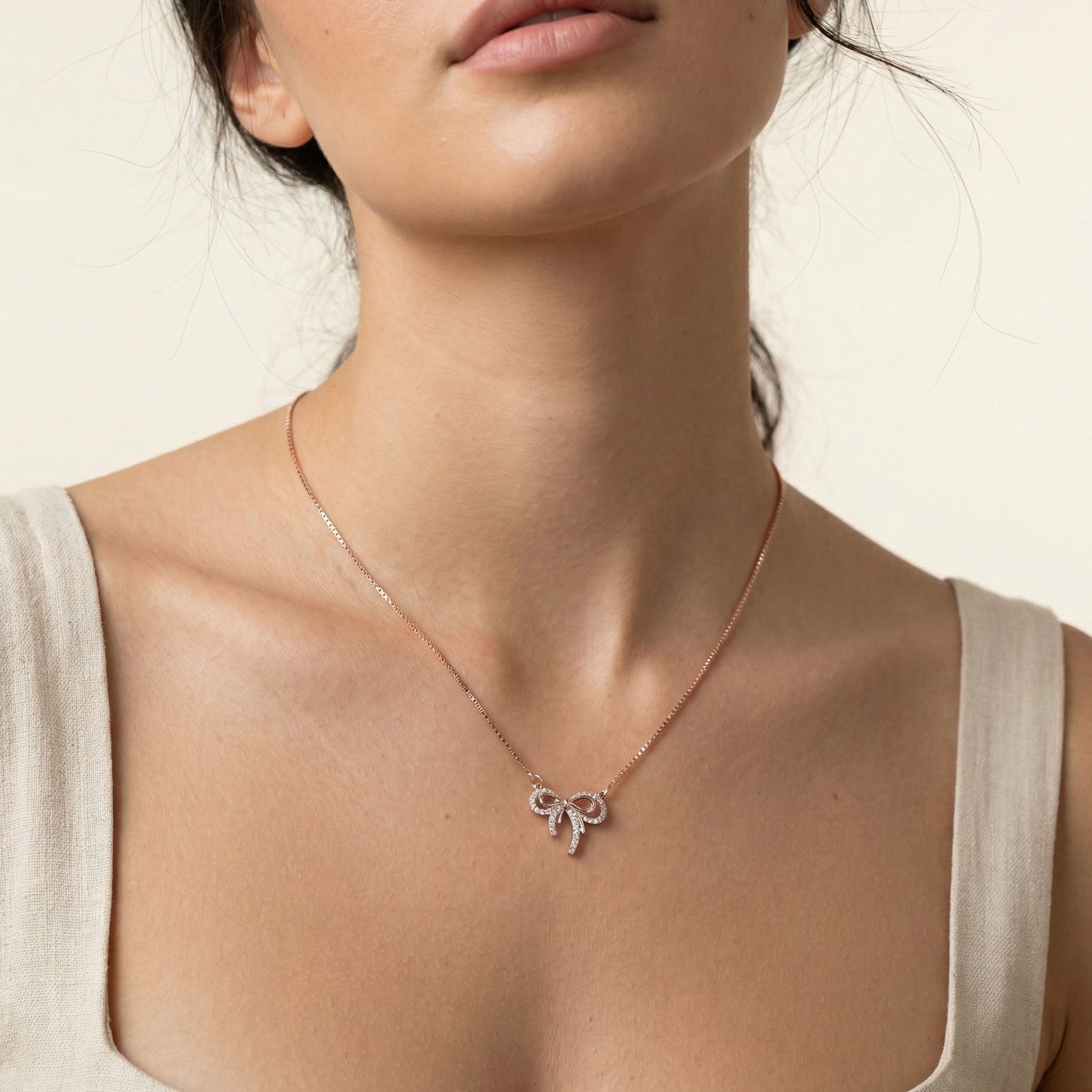 Necklace with a rose gold bow pendant worn by a person on a neutral background, sterling silver pendant, Sterling silver, Bow pendant, pendant for her