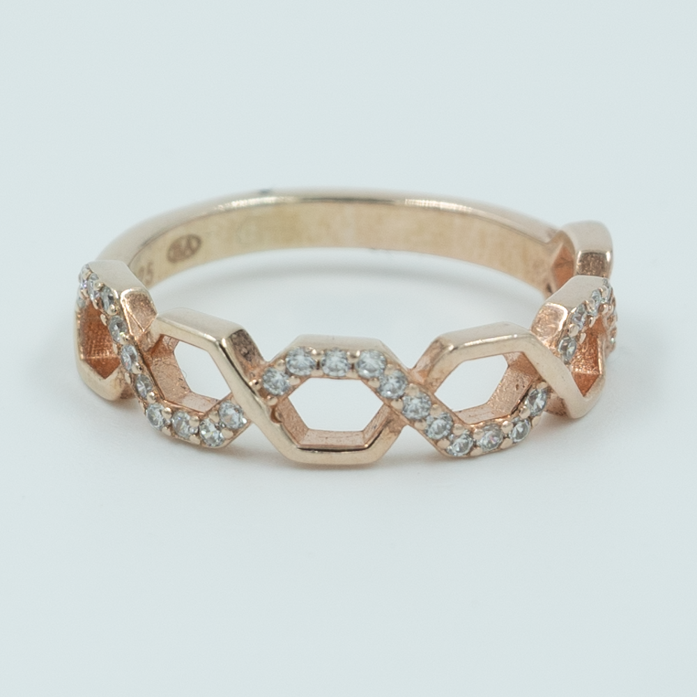 A silver ring with a honeycomb-inspired design, featuring interlocking hexagons and a halo of zircon stones around the band. it's in rose gold.