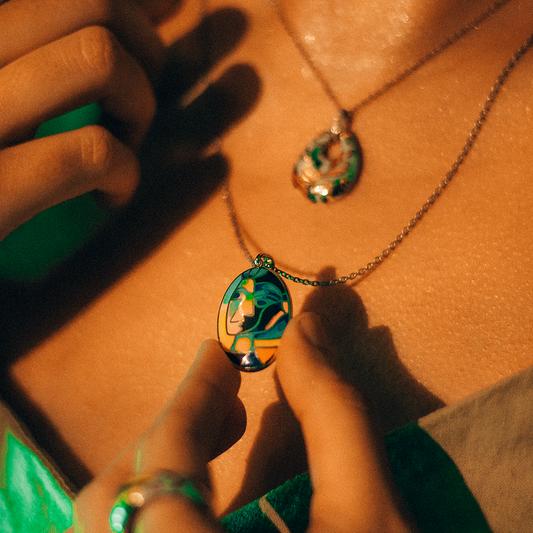 Close-up of a person wearing Modern muse set which has an abstract female face enameled on the pendant showing modern design