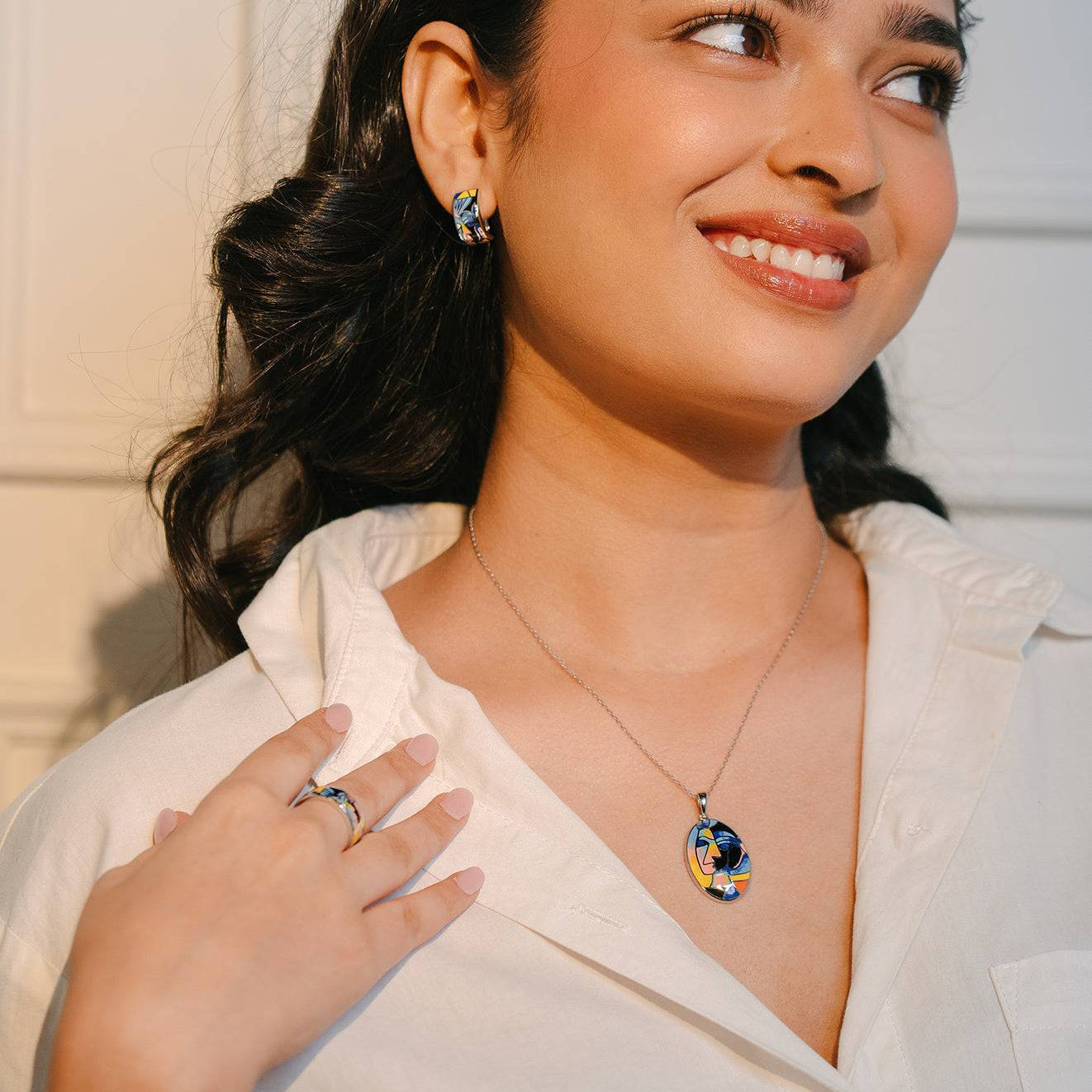 A sterling silver enamel set with pendant earrings and ring set with print of a modern muse on a model