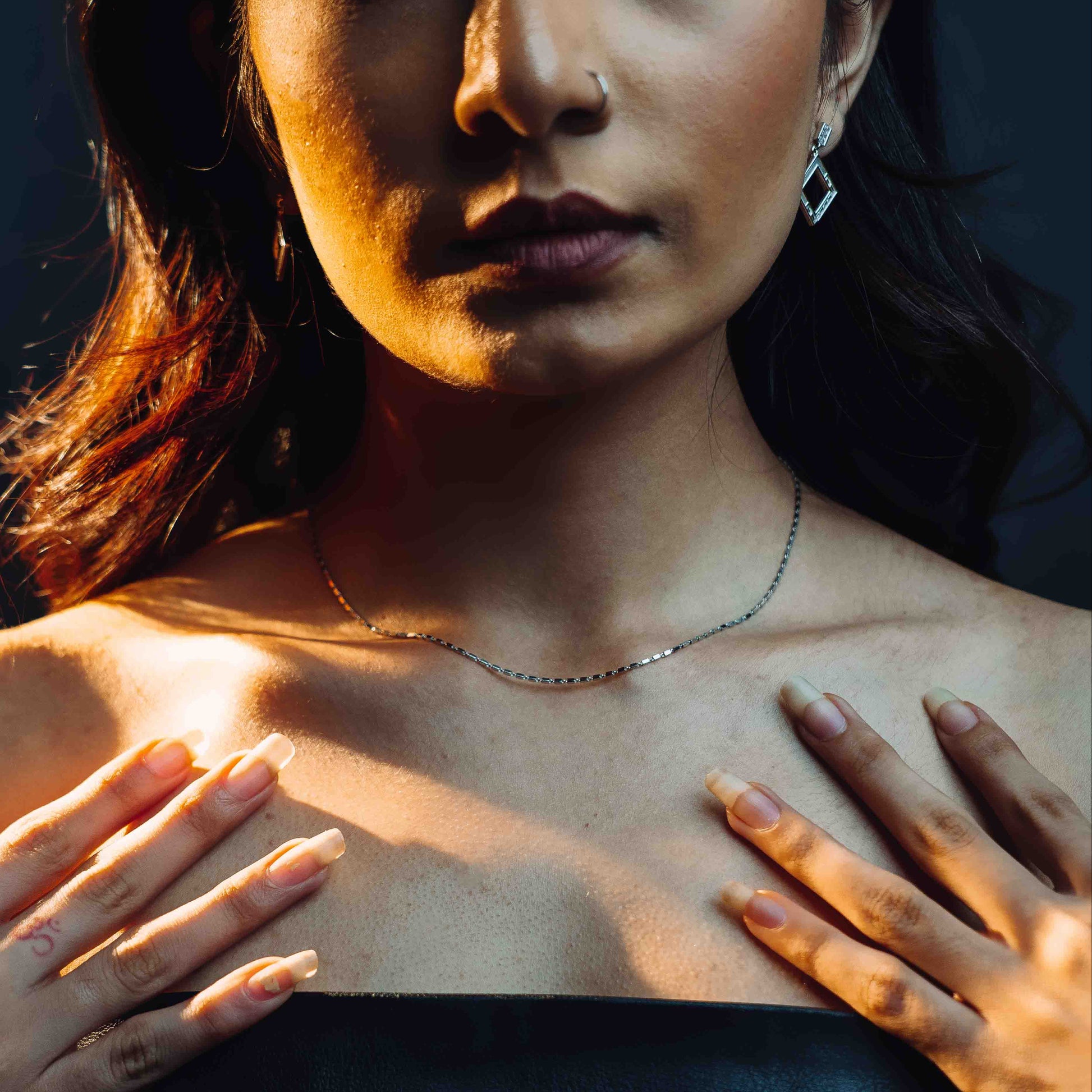 A sterling silver chain which has tiny rectangles interlocked with square MOP earrings lifestyle look