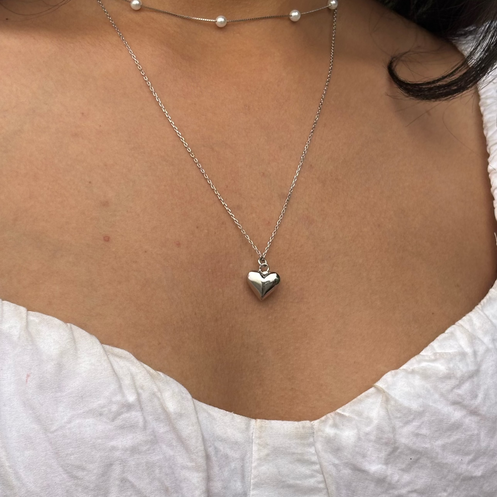 Stunning liquid heart pendant in rhodium plating on neck of a model