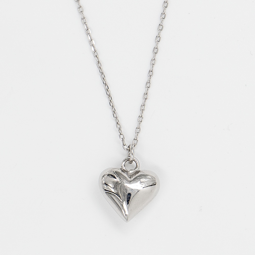 A rhodium plated silver heart-shaped pendant on a rhodium plated silver chain against a white background.