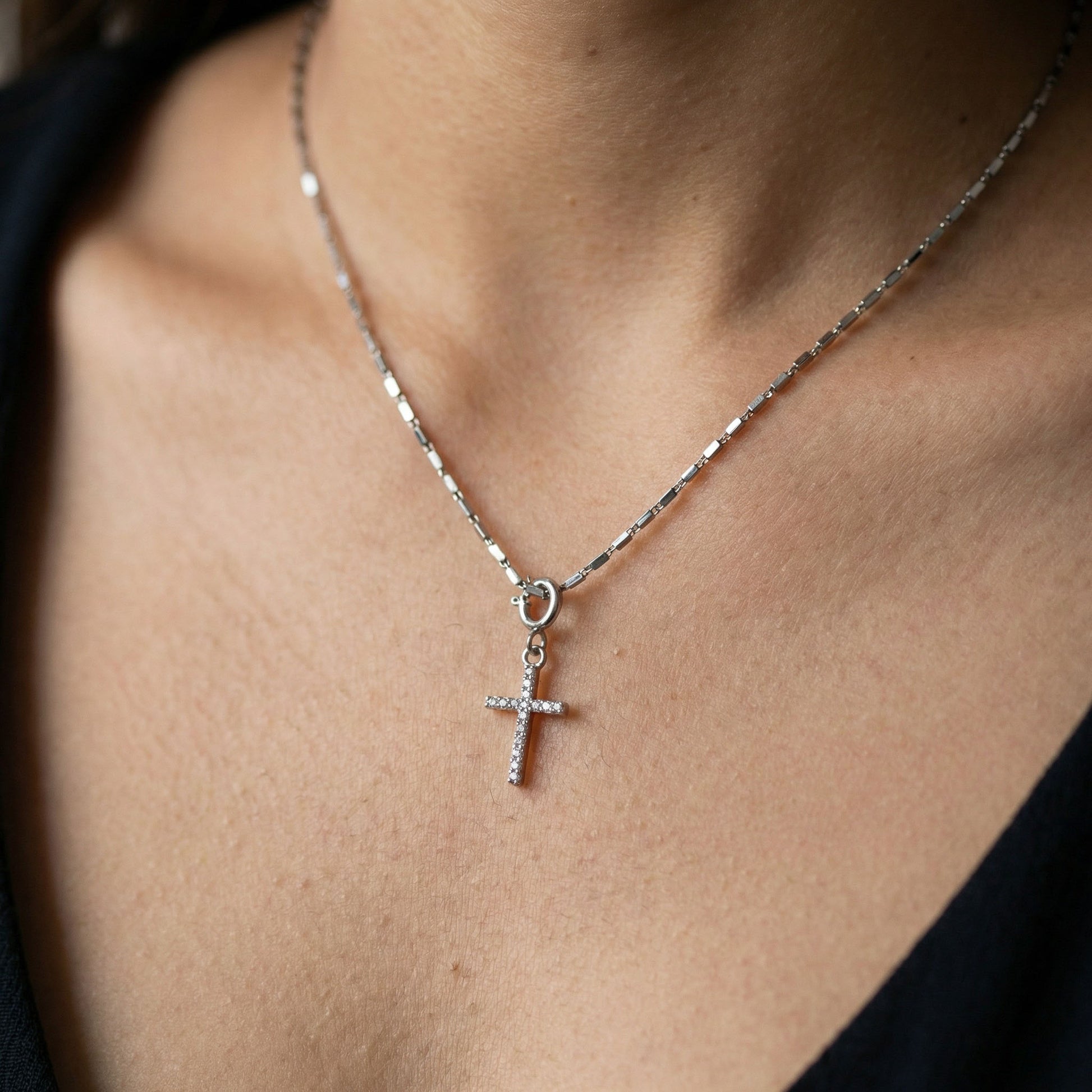 Cross charm in silver, worn with a chain. Silver charms