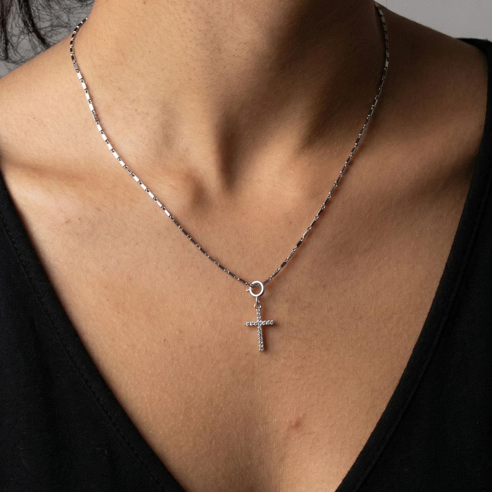 Silver cross charm on neck with a chain