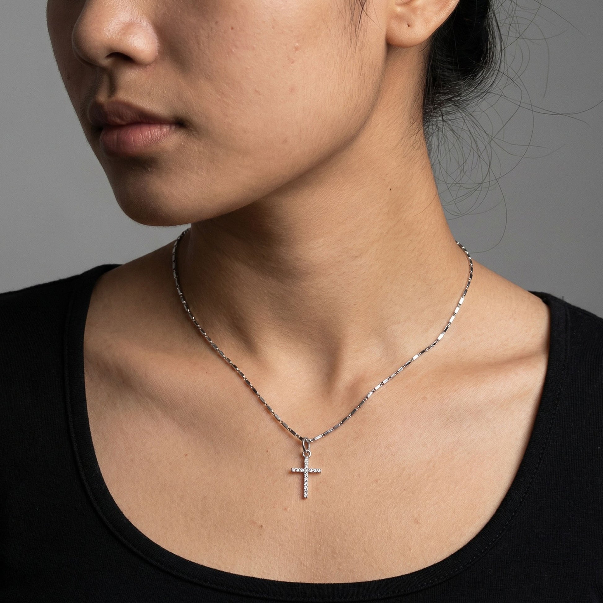 Silver cross charm worn on a chain